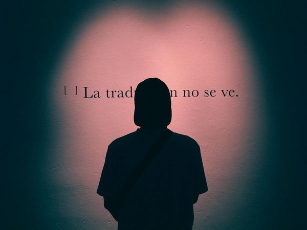 Silhouette of a person meditating against a background with pink light accents.